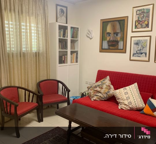 חדר מסודר עם ספה, כורסאות, שולחן וציורים על הקיר